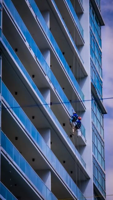 A man cleaning skyscraper windows with a harness, showcasing urban high-rise work.